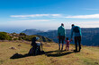 © Chris - Hiker parents with small child walking on meadow overlooking coastline of Atlantic Ocean on Madeira island, Portugal, Europe. Idyllic hiking trail to mountain peak Pico Ruivo. Happy family concept