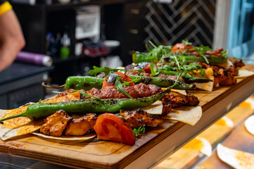 Wooden plate with Turkish mixed grill meat, chicken wings, lamb, beef shashlik, kebab, peppers from charcoal grill in restaurant