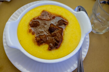 Wall Mural - Traditional first course for lunch or dinner in Italy, yellow corn polenta porridge with stew served in Italian restaurant, Milan, Italy