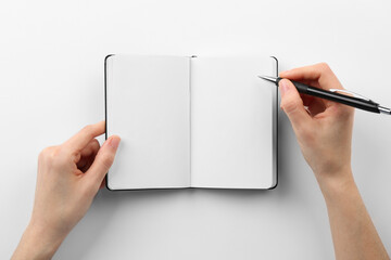 Wall Mural - Woman writing in notebook on white background, top view