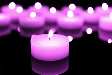 Wall Mural - Burning violet candle on black background, closeup. Funeral attributes