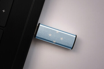Wall Mural - usb flash drive in notebook computer with the national flag of Federated States of Micronesia on gray background.