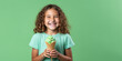 Young smiling girl is holding green ice cream waffle cone on green background