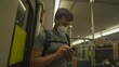 Male wearing mask use mobile phone while commuting in old subway in Munich, Germany. U bahn in Munchen. Keep social distancing to crowd while commuting in metro. Coronavirus and public transportation