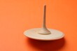 One wooden spinning top on orange background, space for text