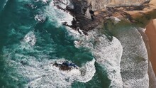 Top-down view of the ocean waves crashing on the rocks. Slow motion footage