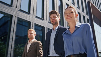 Business team walking urban street close up. Happy colleagues strolling downtown