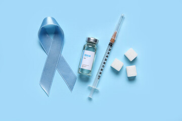 Wall Mural - Awareness ribbon with insulin, syringe and sugar cubes on blue background. Diabetes concept