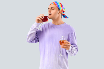 Poster - Young man drinking wine on grey background