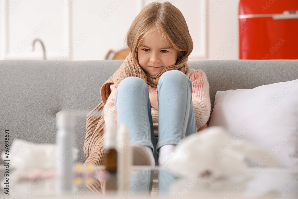 Sick little girl sitting on sofa at home