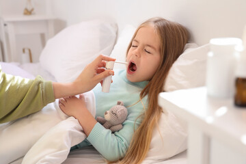 Sticker - Mother spraying sore throat of her sick little daughter in bedroom