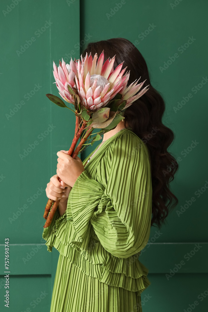 Young woman with beautiful protea flowers on green background