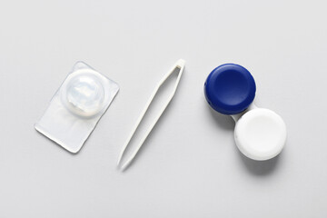 Poster - Tweezers with container and contact lens on white background