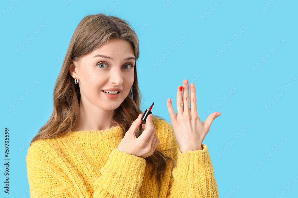 Young woman with nail polish brush on blue background