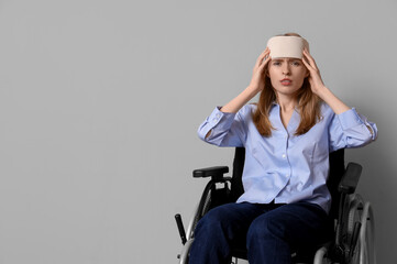 Canvas Print - Young woman with brain concussion in wheelchair on light background