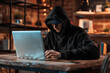 A computer hacker stealthily stealing data from a laptop, illustrating the dangers of identity theft and cybercrime.






