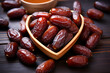 A heart-shaped bowl brimming with ripe, wrinkled dates, set against a rustic dark wood backdrop, evokes a sense of wholesome, natural sweetness