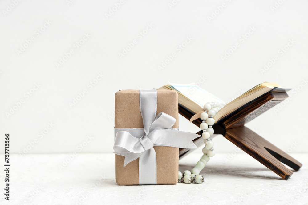 Gift box with Koran and prayer beads for Ramadan on white table