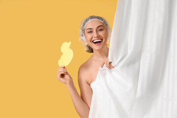 Sticker - Young woman in shower cap with paper duck behind bathroom curtain on yellow background