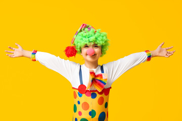 Poster - Funny little boy in clown costume on yellow background. April Fools Day celebration