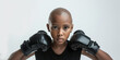 Bald African-American teenage girl with face of anger determination in boxing gloves ready to fight cancer any disease challenge on white background. Teenager fighting with dangerous illness concept