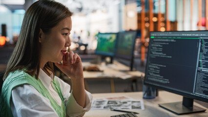 Aufkleber - Female Asian Game Programmer Coding On Desktop Computer In Game Development Studio Diverse Office. Focused Woman Writes Lines Of Code, Does AI Engineering For New Immersive 3D Survival Video Game