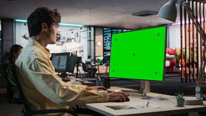 Aufkleber - Portrait of Creative Caucasian Man Sitting at a Desk Using Desktop Computer with Mock-up Green Screen Chromakey. Male Concept Artist Working in Game Design Startup Office, Creating Immersive Gameplay.