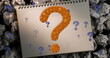 Image of question marks over notebook and paper