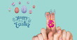 Image of happy easter, eggs and fingers paint as bunnies on mint background