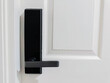 Closeup of black digital door lock handle on  white wooden door