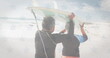 Image of flag of united states of america over senior biracial couple with surfboard on beach