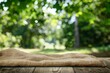 Nature background and table wood for product display template, Empty wooden table and sack tablecloth over blur green tree at park, garden outdoor with bokeh light background - generative ai