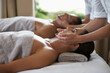 © Katie/peopleimages.com - Hands, face massage and couple in spa to relax on bed for luxury pamper treatment together in hotel. Beauty, facial or zen woman with man at resort or salon for natural healing benefits or skincare