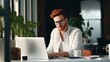 © liliyabatyrova - A handsome, confident, Stylish redhead man, businessman with glasses, sits at a desk and works on a laptop in a bright office with indoor plants. Business, Freelance, Startup, Work, Modern Technology.