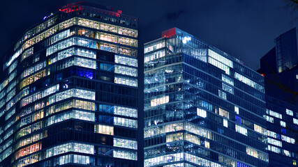 Wall Mural - Office building at night, building facade with glass and lights. View with illuminated modern skyscraper.