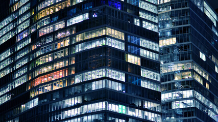 Wall Mural - Office building at night, building facade with glass and lights. View with illuminated modern skyscraper.