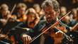 An adult man plays the violin in a symphony orchestra on a blurred background.