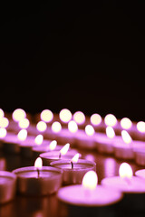 Poster - Beautiful burning violet candles on black background. Funeral attributes