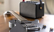 Black electric guitar and speaker on a wooden table.
