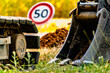 © Reflexpixel - Arm of a mini digger and bucket with a speed limit sign at 50, road sign