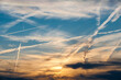 Morgen- oder Abendhimmel mit auf- oder untergehender von den Wolken verdeckter Sonne und Gewirr von sich kreuzenden, teilweise auflösenden Kondensstreifen