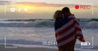 Young couple wrapped in American flag on beach, captured on camera in 4k.