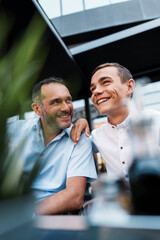 Handsome and happy father and his teenager son sitting in a restaurant and talking.