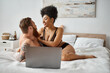 © LIGHTFIELD STUDIOS - interracial couple having fun near laptop on bed, african american woman and bearded tattooed man