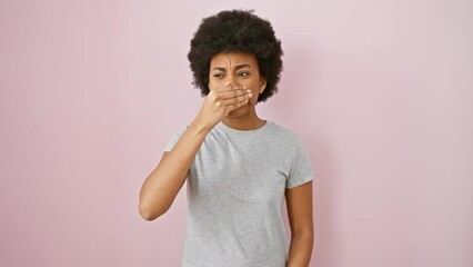 Poster - Shocked african american woman in t-shirt peeks through fingers! afraid yet fun, standing against an isolated pink background, covering eyes with hand.