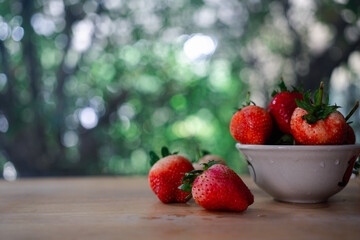 Red fresh strawberry in a bowl against nature background.