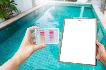 Wall Mural - Girl hand holding water testing test kit with blank report sheet in girl hand over swimming pool background, swimming pool water testing, pool service and maintenance