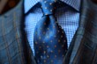 A striking blue tie with tiny gold patterns, perfectly complementing the blue hued shirt it's paired with