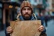 Bearded young man looking hopeful holding a blank cardboard sign that can represent any message or cause