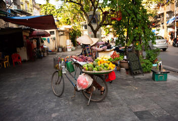 Wall Mural - Vietnam street vendors. Woman with traditional Vietnamese hat selling fruit from bicycle in Hanoi